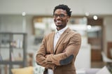 Cropped portrait of a confident young businessman standing with his arms folded in his office